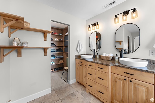 bathroom with a sink, visible vents, tile patterned floors, and double vanity