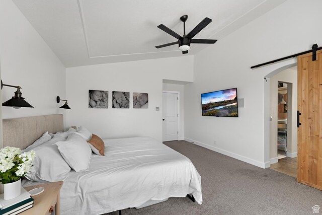 carpeted bedroom featuring baseboards, arched walkways, a barn door, ceiling fan, and vaulted ceiling