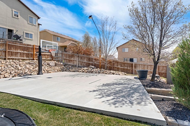 exterior space with basketball hoop, fence, and a residential view
