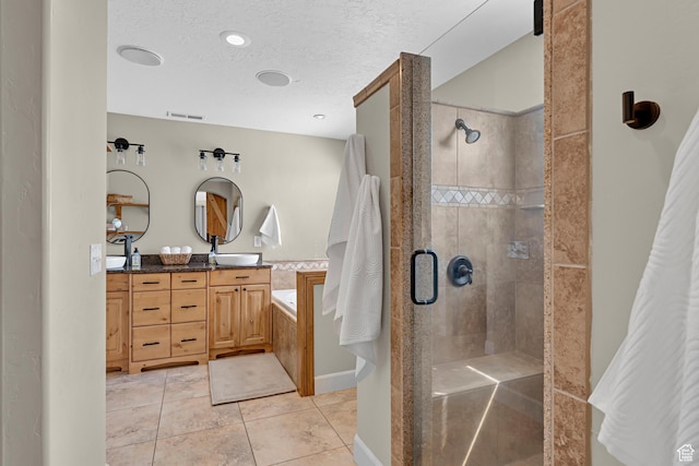 full bathroom with a garden tub, a shower stall, a textured ceiling, visible vents, and a sink