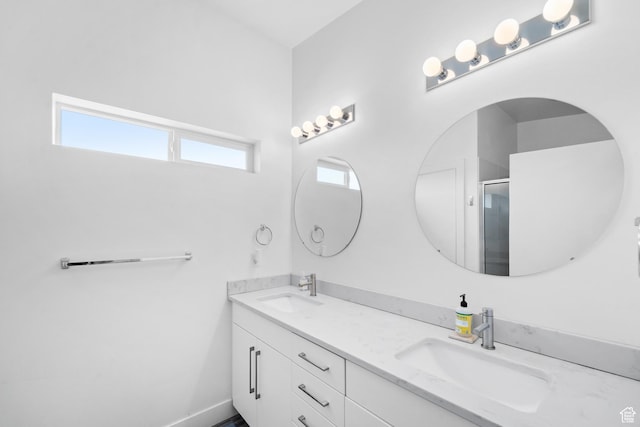 full bathroom featuring a sink, an enclosed shower, baseboards, and double vanity