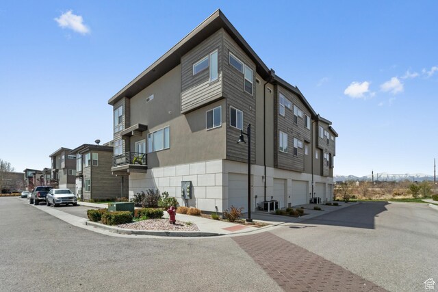 view of building exterior featuring a garage, a residential view, and central AC