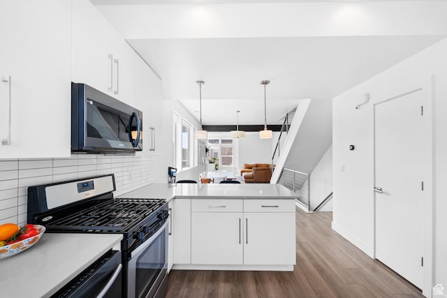 kitchen featuring white cabinets, a peninsula, light countertops, and stainless steel range with gas cooktop