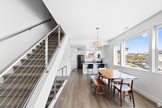 dining area with visible vents, baseboards, stairway, and wood finished floors
