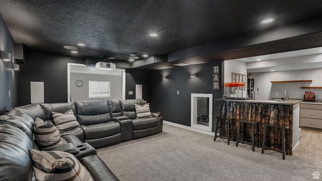 home theater room featuring baseboards, wet bar, a textured ceiling, recessed lighting, and light carpet
