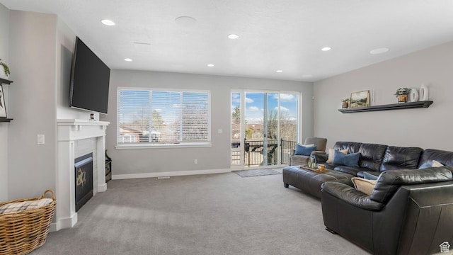 living room featuring baseboards, recessed lighting, light colored carpet, and a glass covered fireplace