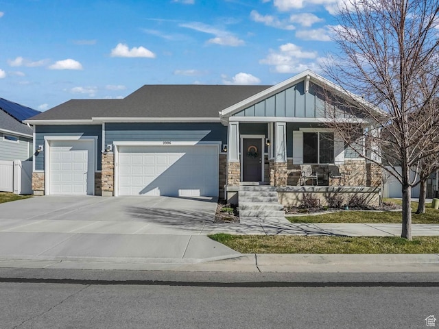 view of front facade featuring concrete driveway, stone siding, board and batten siding, a porch, and a garage