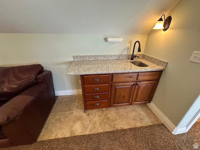 1234 S Parkway Blvd E Unit 725, Saratoga Springs, UT 84045 - interior space with baseboards, a sink, a textured ceiling, brown cabinetry, and light stone countertops