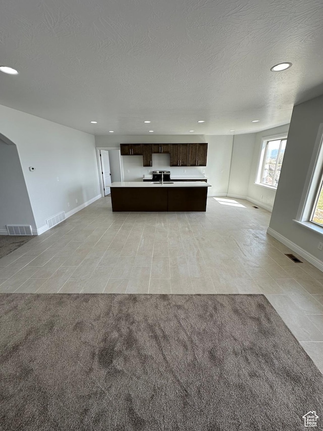 1234 S Parkway Blvd E Unit 725, Saratoga Springs, UT 84045 - kitchen with open floor plan, light carpet, dark brown cabinets, and visible vents