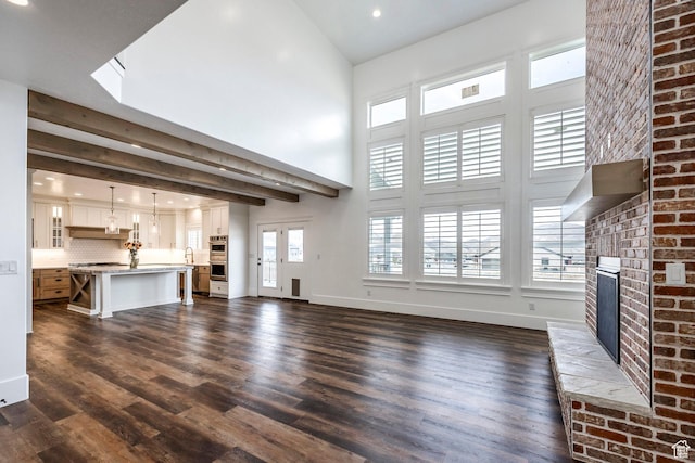 159 E 625 S, Mantua, UT 84324 - unfurnished living room featuring a brick fireplace, dark wood-type flooring, a high ceiling, recessed lighting, and baseboards