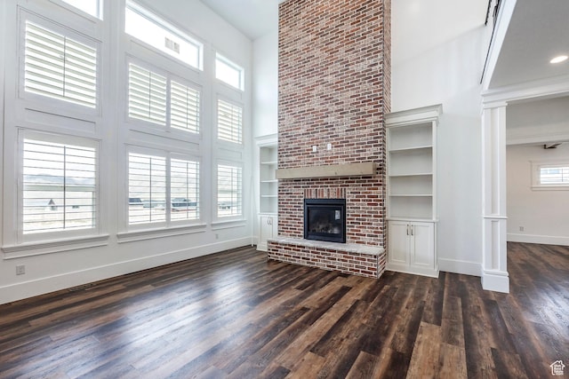 159 E 625 S, Mantua, UT 84324 - unfurnished living room featuring a high ceiling, baseboards, dark wood-style flooring, a brick fireplace, and ornate columns
