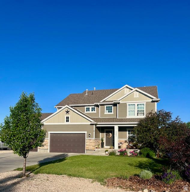 1962 Bluff Crest Rd Unit 4, Francis, UT 84036 - view of front of home featuring covered porch, a front lawn, concrete driveway, a garage, and board and batten siding