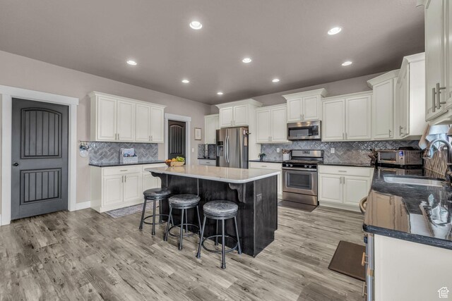 1962 Bluff Crest Rd Unit 4, Francis, UT 84036 - kitchen featuring light wood-type flooring, a breakfast bar, white cabinetry, stainless steel appliances, and a sink