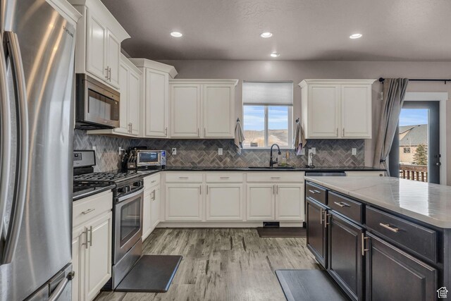 1962 Bluff Crest Rd Unit 4, Francis, UT 84036 - kitchen featuring white cabinets, a sink, light wood finished floors, stainless steel appliances, and decorative backsplash