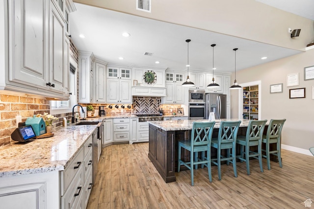 1125 S 400 E, Salem, UT 84653 - kitchen with tasteful backsplash, light wood-type flooring, visible vents, a breakfast bar, and appliances with stainless steel finishes