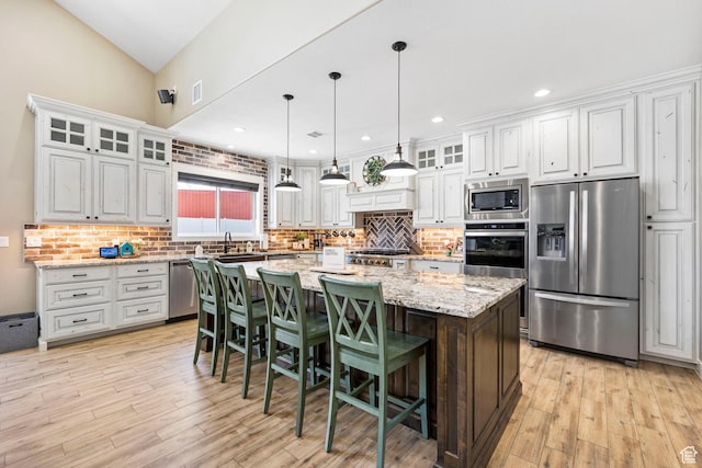 1125 S 400 E, Salem, UT 84653 - kitchen featuring a center island, appliances with stainless steel finishes, light wood-style floors, decorative backsplash, and a breakfast bar area