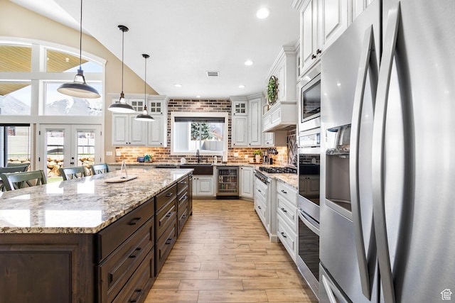 1125 S 400 E, Salem, UT 84653 - kitchen with dark brown cabinetry, tasteful backsplash, white cabinetry, appliances with stainless steel finishes, and a center island with sink
