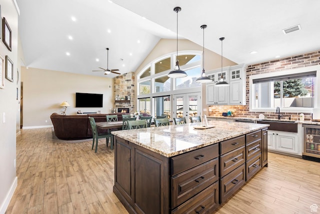 1125 S 400 E, Salem, UT 84653 - kitchen with light wood-type flooring, white cabinetry, visible vents, wine cooler, and a sink