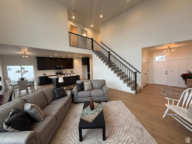 3758 W Alder Ct, Taylor, UT 84401 - living room featuring light wood-style flooring, a towering ceiling, recessed lighting, a chandelier, and stairs