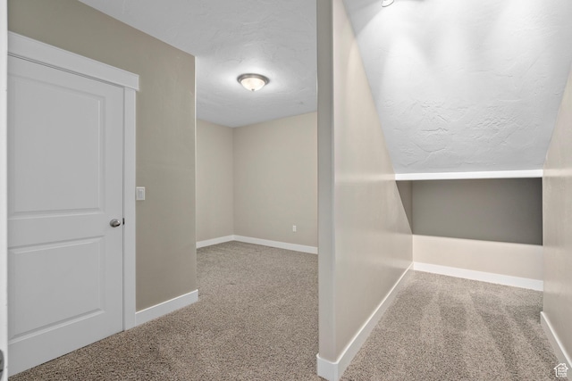 hallway featuring baseboards, carpet, and a textured ceiling