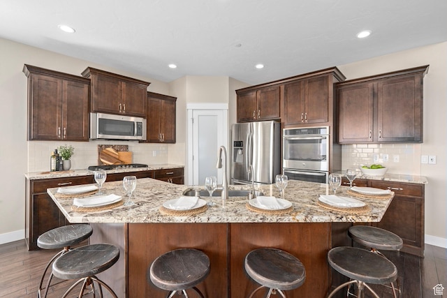 kitchen featuring stainless steel appliances, a kitchen bar, a sink, and dark brown cabinets