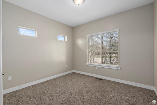 carpeted empty room featuring visible vents and baseboards