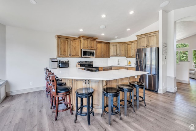 4071 S Sandpiper Ln, Saratoga Springs, UT 84045 - kitchen with light wood-style flooring, a peninsula, appliances with stainless steel finishes, and a breakfast bar area