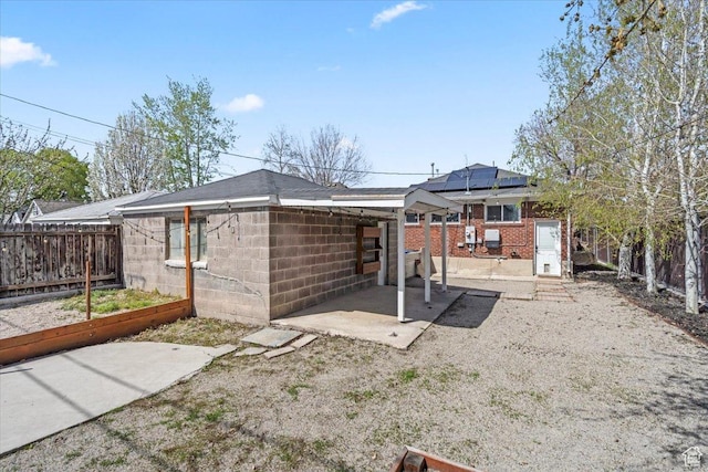 rear view of house with a patio area, a garden, fence, and solar panels