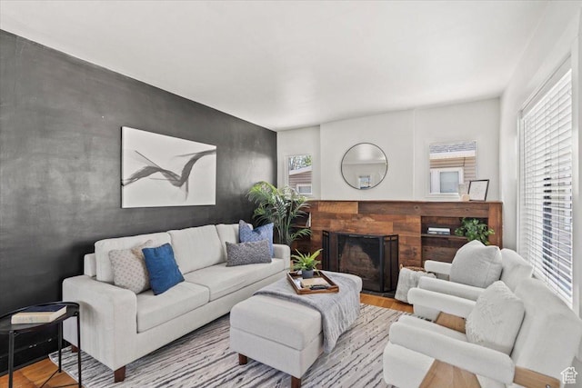 living area featuring a fireplace, an accent wall, and wood finished floors