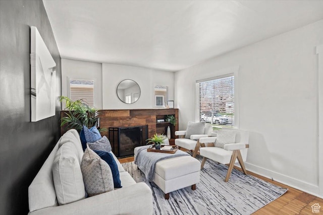 living area featuring a fireplace, baseboards, and wood finished floors
