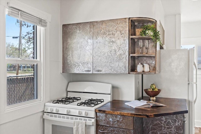 kitchen featuring dark brown cabinets, open shelves, dark countertops, and white appliances