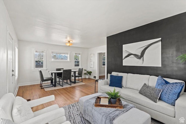 living area with an accent wall, baseboards, and hardwood / wood-style floors