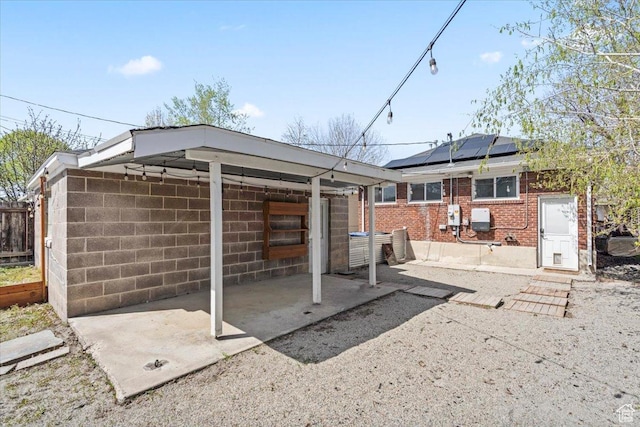 exterior space with concrete block siding, solar panels, and brick siding