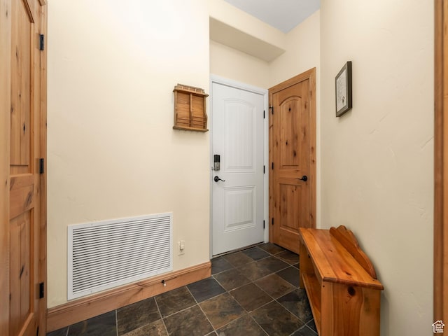 foyer featuring visible vents, baseboards, and stone finish flooring