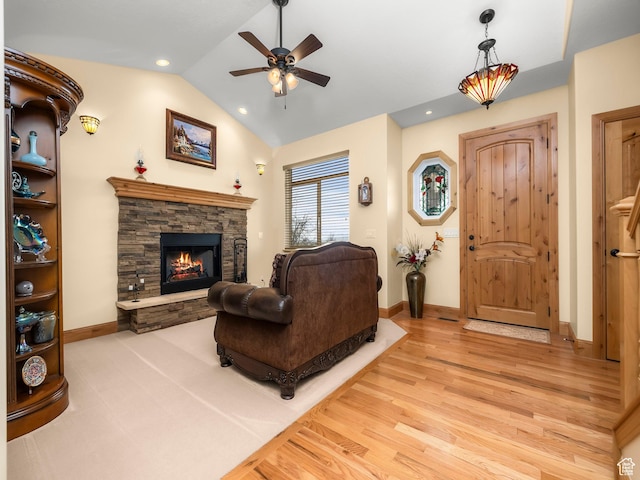 living area featuring baseboards, ceiling fan, a fireplace, wood finished floors, and lofted ceiling