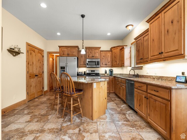 kitchen with brown cabinets, appliances with stainless steel finishes, a kitchen bar, and a sink