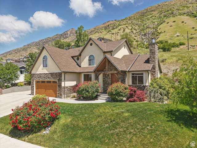 1411 S Slate Canyon Dr, Provo, UT 84606 - view of front of home with stone siding, stucco siding, a chimney, driveway, and a mountain view