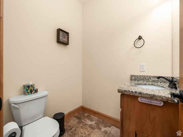 bathroom with toilet, vanity, and baseboards
