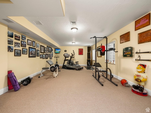 exercise area featuring a textured ceiling, baseboards, and visible vents