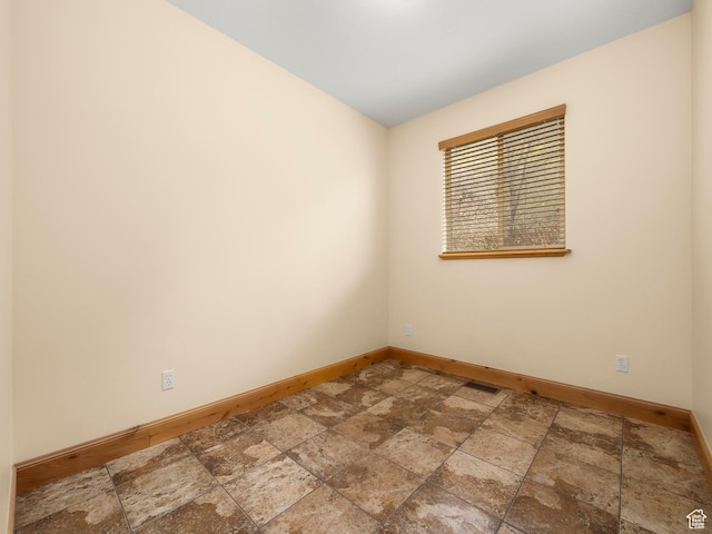 empty room featuring visible vents, baseboards, and stone finish floor