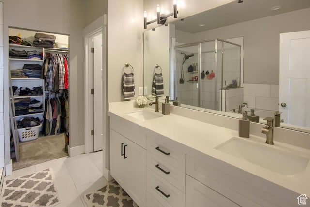bathroom featuring a sink, a spacious closet, a shower stall, double vanity, and tile patterned flooring