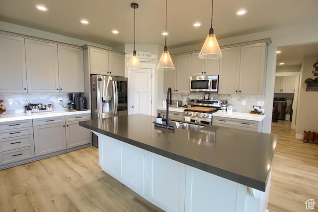 kitchen featuring tasteful backsplash, a sink, stainless steel appliances, gray cabinets, and light wood-style flooring