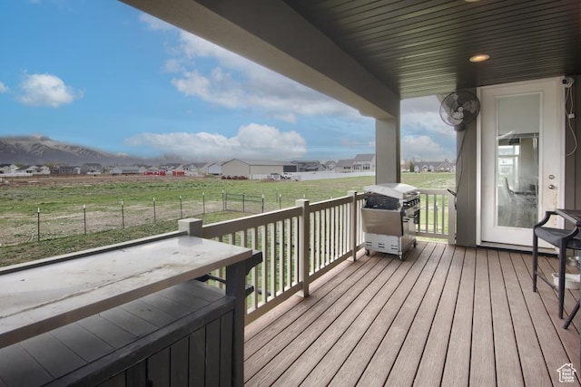 deck featuring a mountain view, a grill, a lawn, and a rural view