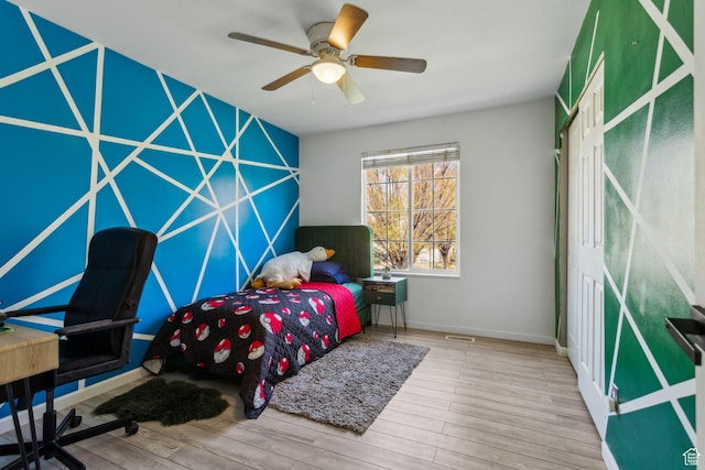 bedroom featuring visible vents, baseboards, ceiling fan, and wood finished floors