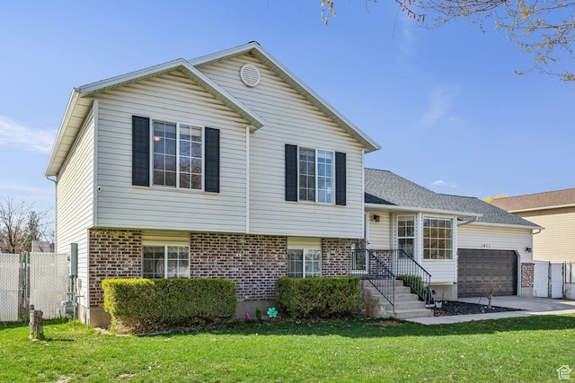 split level home featuring a garage, a front yard, fence, and brick siding