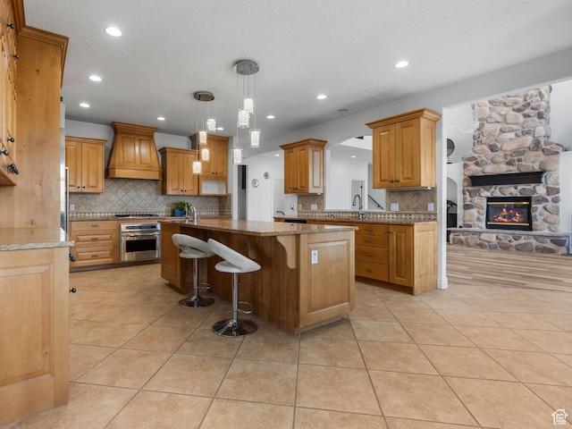 kitchen with premium range hood, oven, a center island, and light tile patterned floors