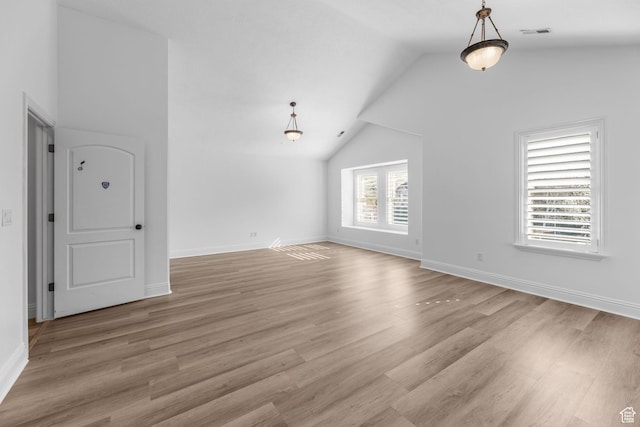 interior space with light wood-style flooring, baseboards, vaulted ceiling, and visible vents