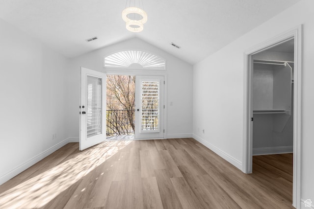 unfurnished dining area with visible vents, a notable chandelier, wood finished floors, and lofted ceiling
