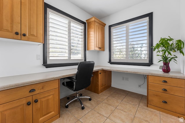 home office with built in desk, light tile patterned floors, and baseboards