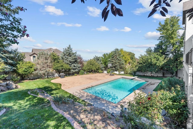 view of swimming pool with a yard, a patio, a fenced backyard, and a diving board